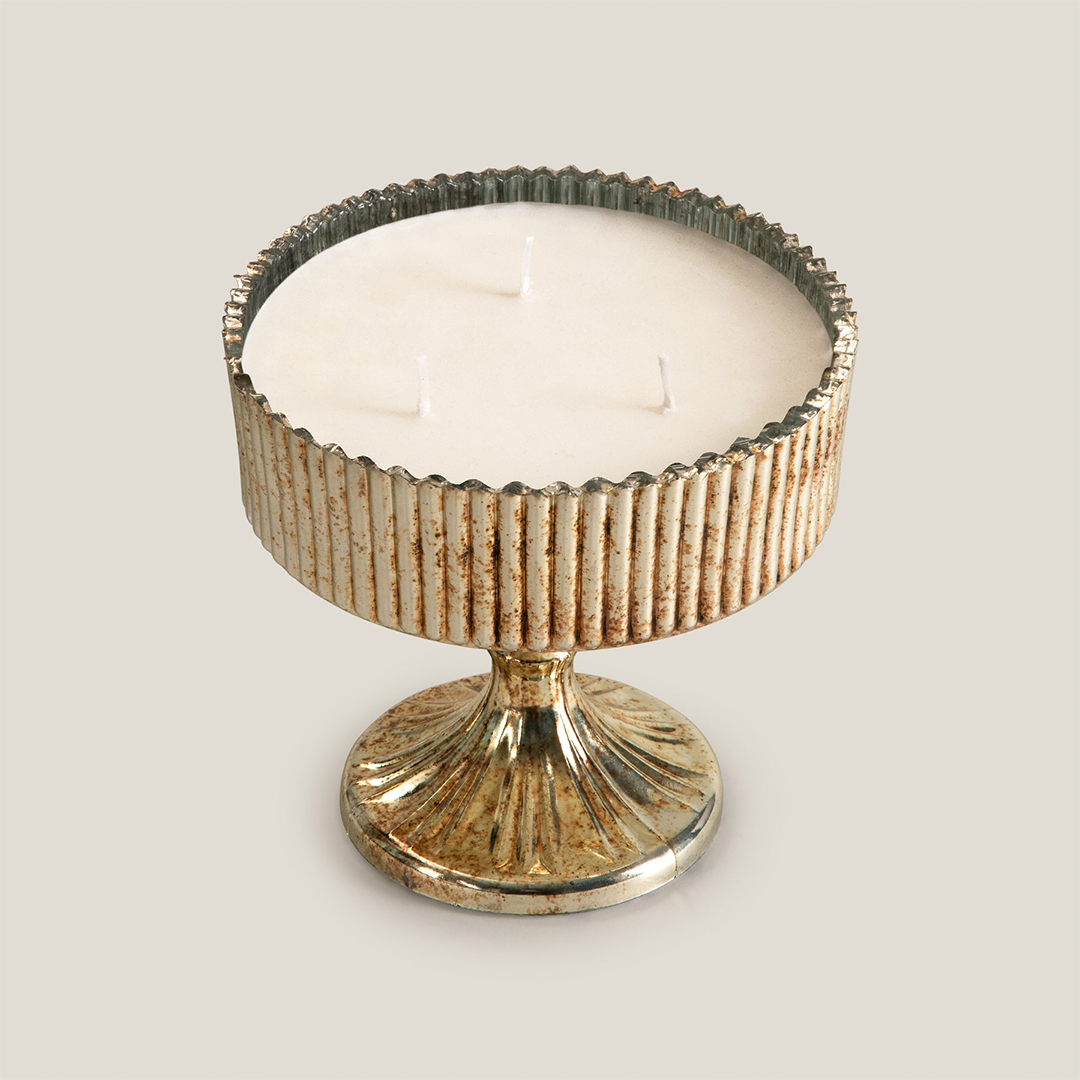 Decorative candle in a ribbed holder on a light gray background
