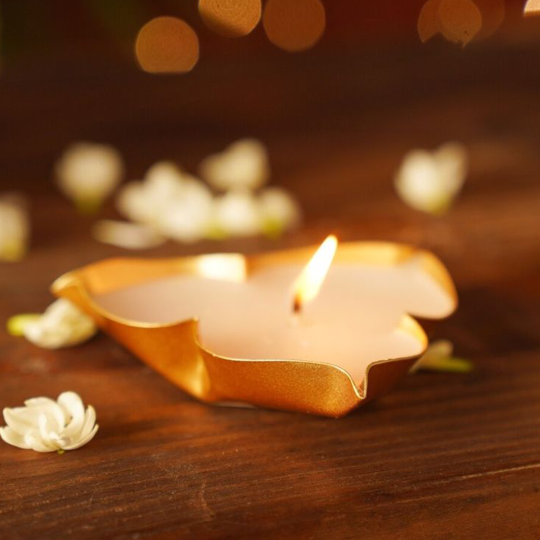 Star-shaped candle with a flame on a wooden surface with blurred lights in the background