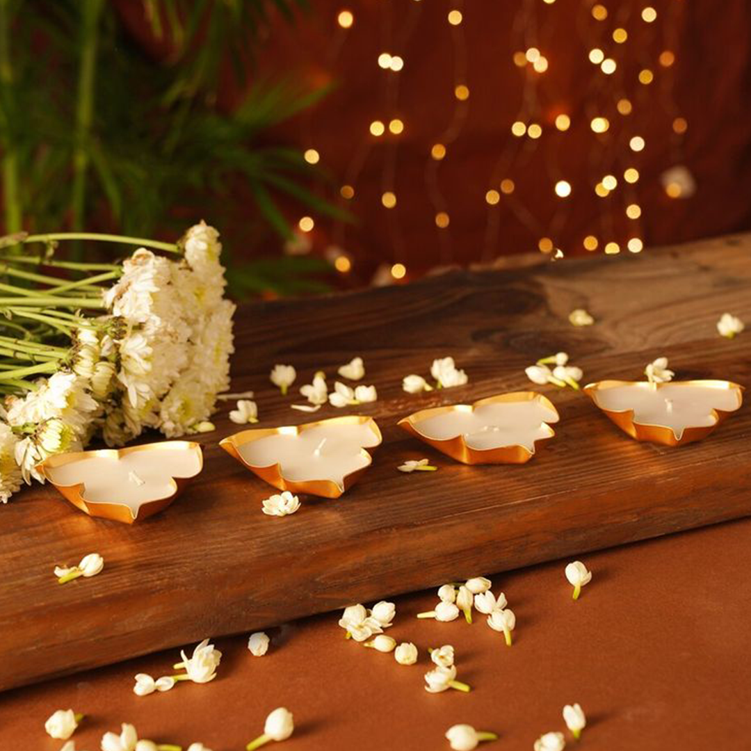 Decorative butterfly-shaped candles on a wooden surface with white flowers and blurred lights in the background