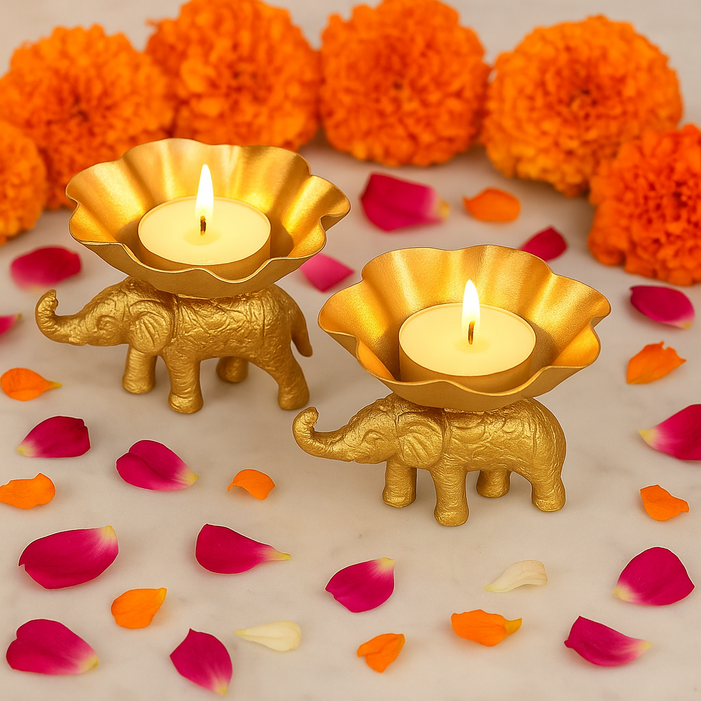 Two gold elephant-shaped candle holders with lit candles on a decorative background with orange and pink flowers and petals.